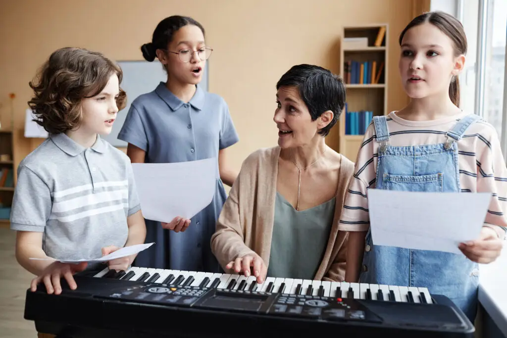 Music teacher singing songs together with children while playing piano in music class